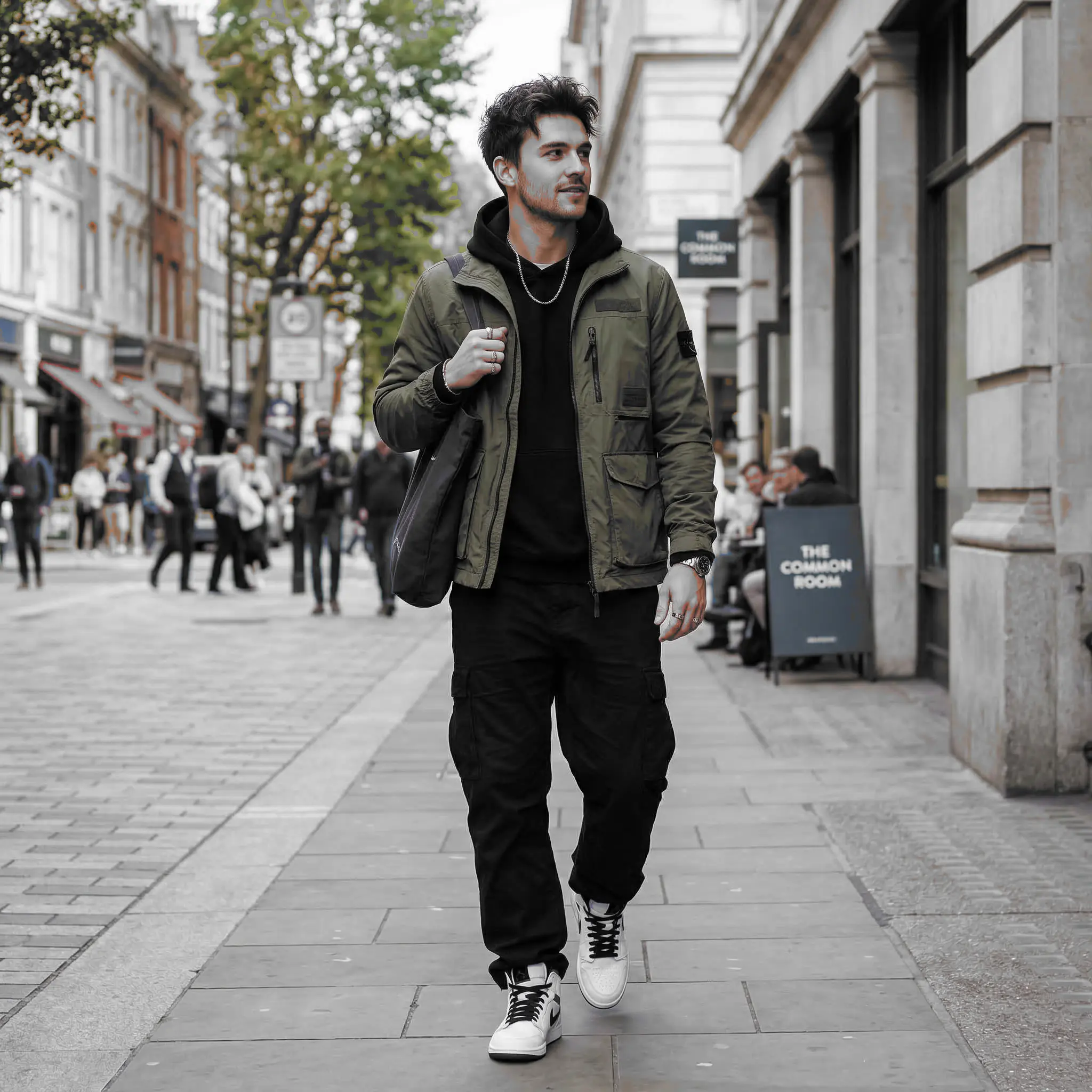 Street portrait with an olive jacket kept in color while the rest of the scene turns grayscale